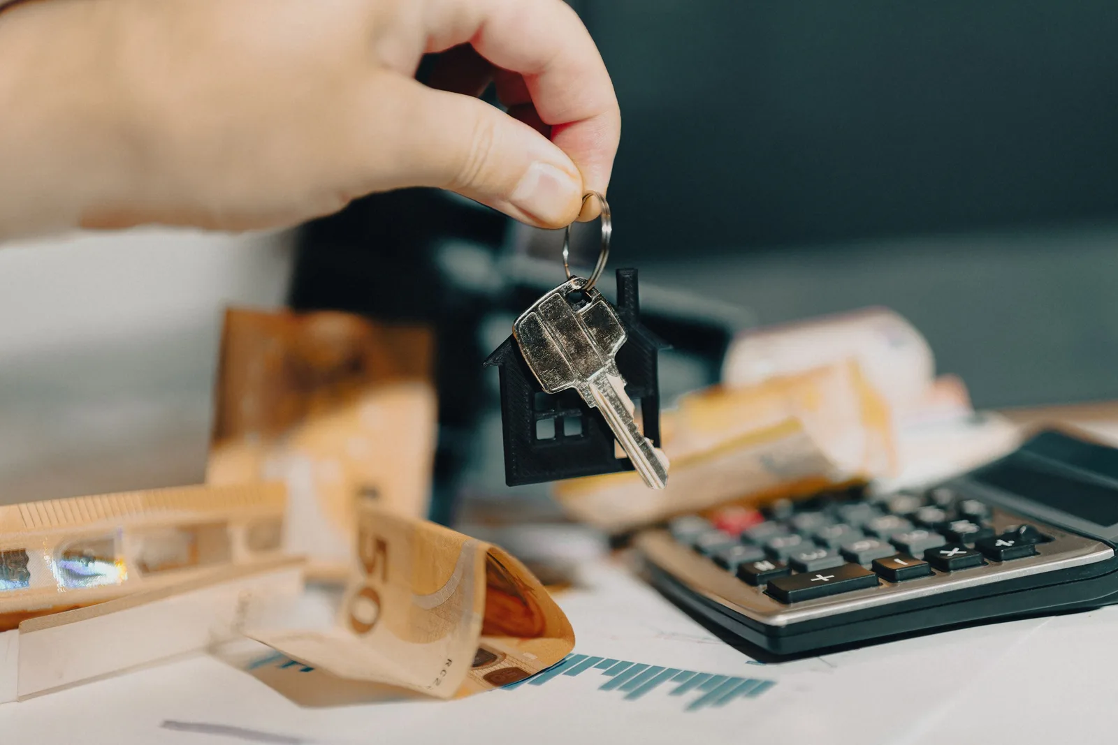 Documentos y calculadora sobre una mesa representando el cálculo de gastos e impuestos al vender un piso