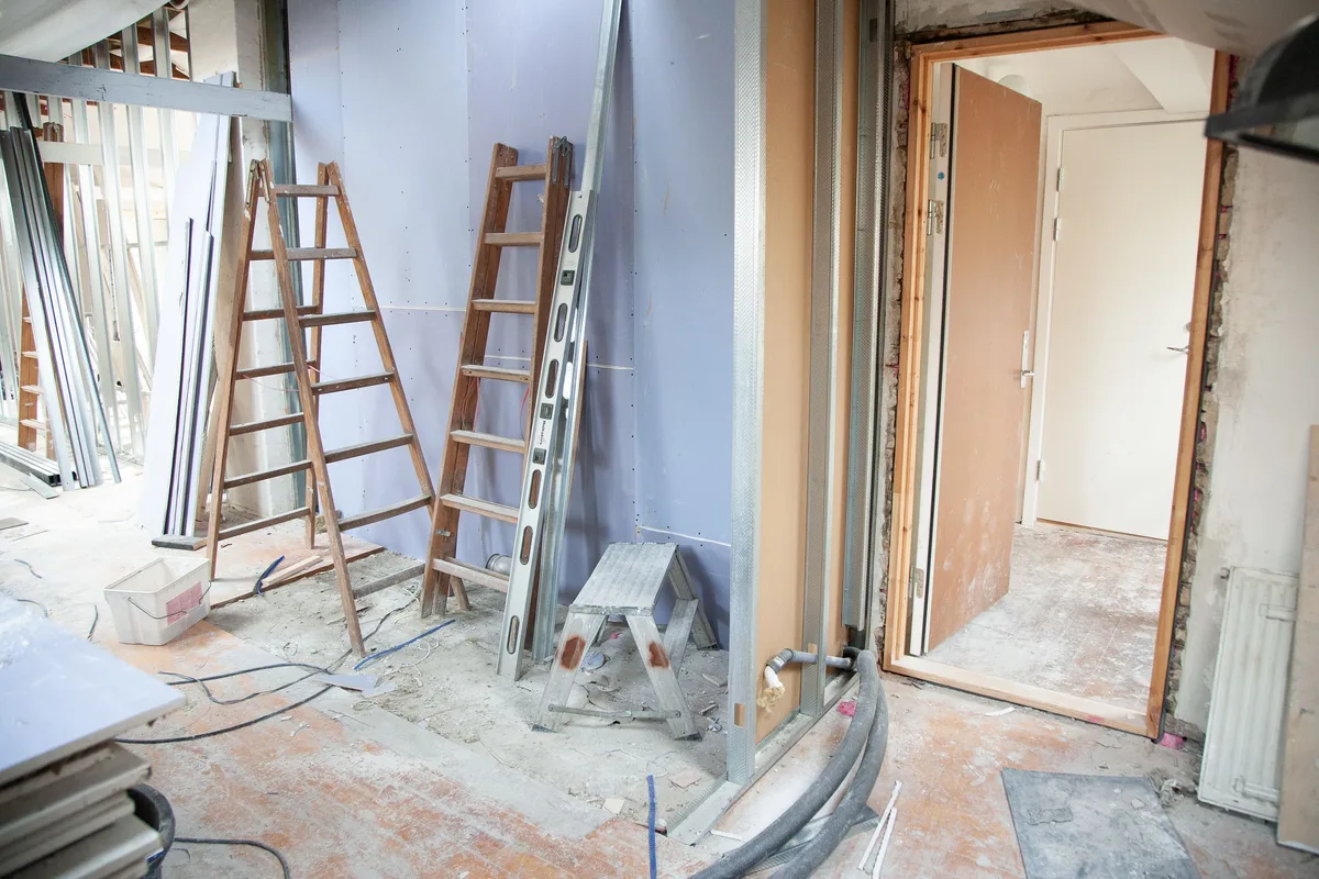 Habitación de una vivienda en obra durante una reforma, con escaleras y herramientas repartidas por el espacio