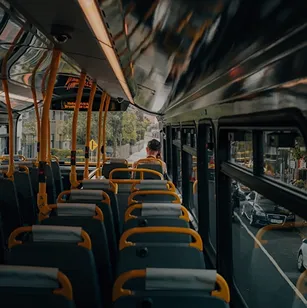 Interior de un autobús urbano con asientos vacíos y pasajeros al fondo