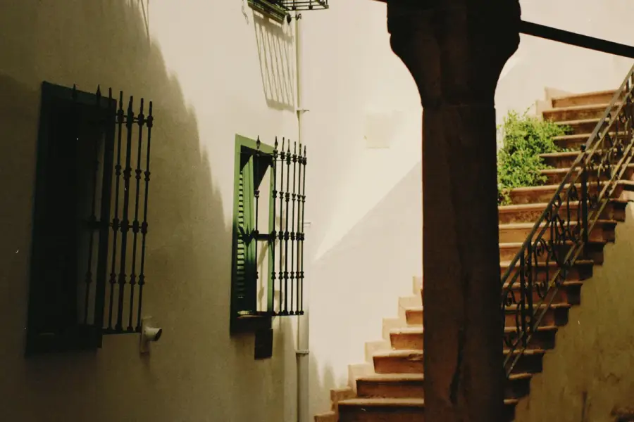 Fachada de vivienda con persianas verdes y juego de luz y sombra bajo el sol mediterráneo